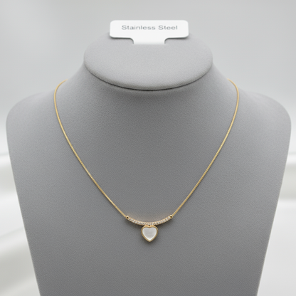 Gold necklace with white heart pendant displayed on jewelry mannequin