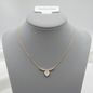 Gold necklace with white heart pendant displayed on jewelry mannequin