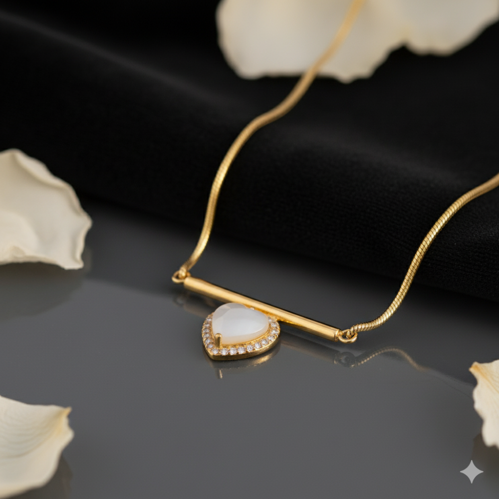 Minimalist gold necklace with white heart pendant placed on black fabric with petals