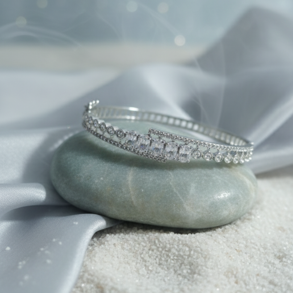Silver crystal bangle bracelet displayed on a stone with soft blue background